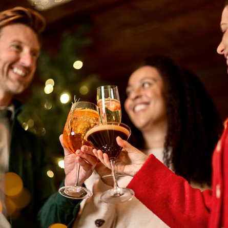 An image of 3 people holding drinks celebrating with a festive cheers at a Chef & Brewer venue.