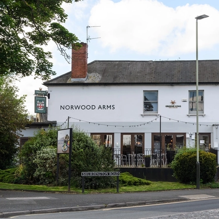 Exterior facade and car park of a pub with a seating area.