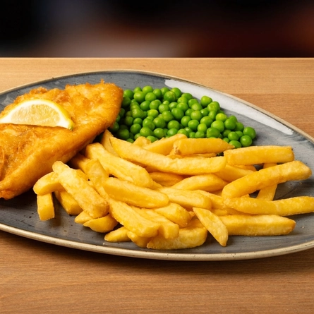 A plate of fish and chips on a wooden table.