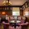 The wood panelled interior restaurant seating area at The Fox, with upholstered chairs, and framed artwork on the walls.