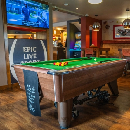 The restaurant seating and gaming area at The Royal Horse, with a TV on the wall and a pool table.