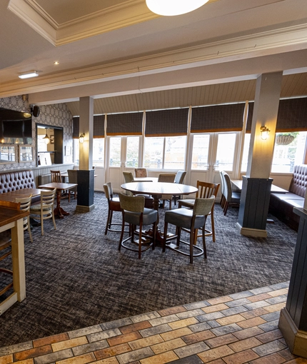 Interior dining area of a pub with a bar and a TV.