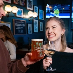 An image of 2 people stood at a table within the restaurant area with a sharer dish and drinks available at Urban Social venues.