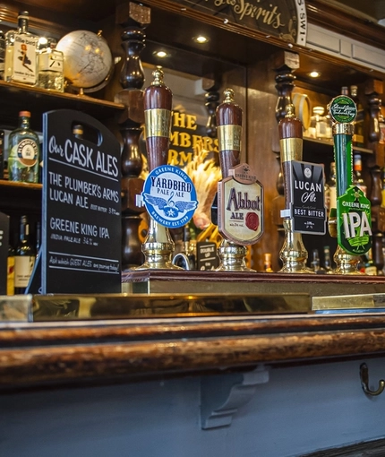 A close up view of the bar, bar taps, and bar stools at The Plumbers Arms in Belgravia.