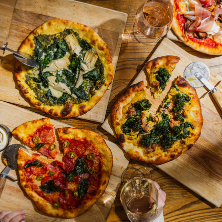 A lifestyle image showing 4 boarded Pizza dishes sat on a table within the interior restaurant seating area at The Four Oaks.