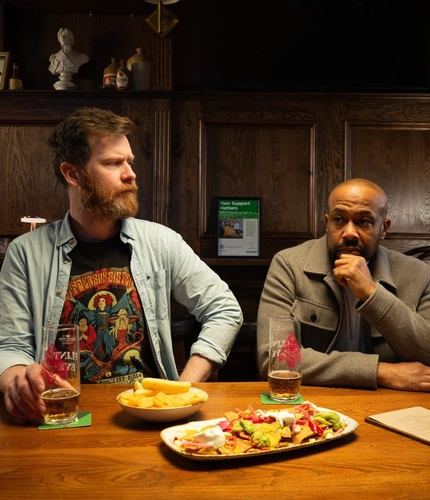 Two men sat at a table with food in front of them.