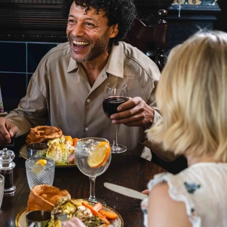 Three people sitting around a table with food and drinks.