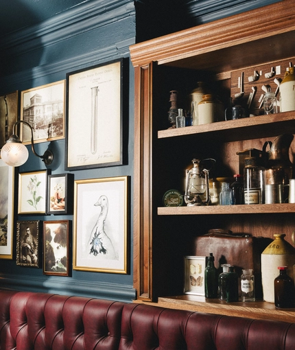 The interior decor of the Sherlock Holmes including framed artwork on the wall and ornaments on wooden shelves.
