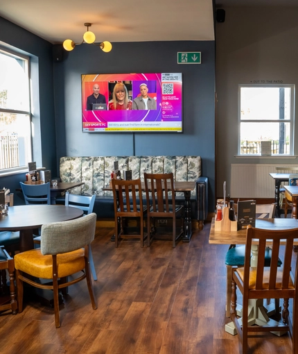 An interior restaurant seating area at The Kittoch, with an upholstered booth seat, and a TV on the wall above it.