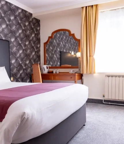 The interior hotel king size bedroom with kingsize bed and dressing table at the Roebuck.