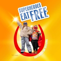 Two children in superhero costumes stand inside a red horseshoe graphic with text that reads “Superheroes Eat Free” and “Superhero Day 28th April” on a bright orange background for Hungry Horse venues.