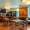 The interior restaurant seating area at the Royal George in Euston; with an upholstered booth seat, a TV on the wall above it, a fireplace, and a large wooden inlay picture of a sailing ship on the wall.