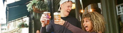 A group of friends in the exterior beer garden and seating area post marathon enjoying drinks in a Greene King London venue.