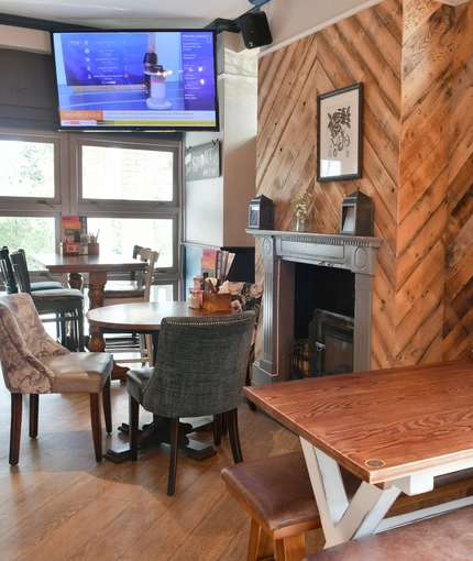 Interior dining area of a pub with a TV and a fireplace.