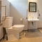 The interior accessible hotel bathroom with toilet and sink at the Cedars Inn.