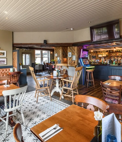 Interior dining area of a pub with a bar, a few gambling machines and a TV.