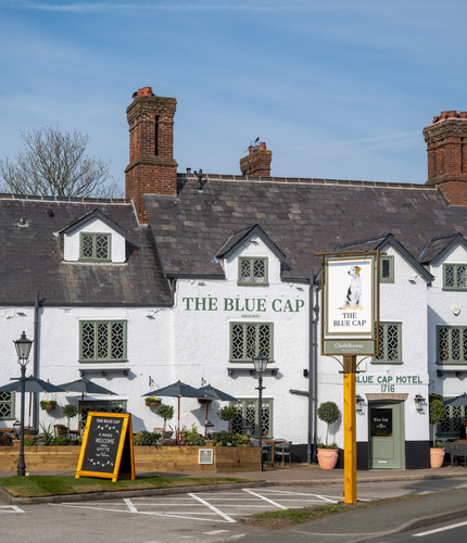 The exterior facade, signage, and seating area of The Blue Cap in Sandiway.
