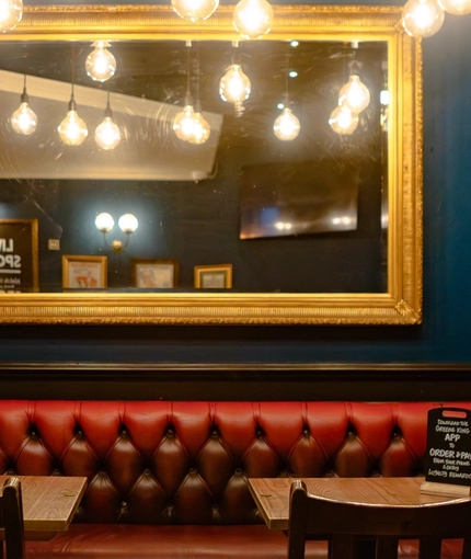 An image of a seating booth within the interior restaurant seating area with ornate lighting and advertising chalkboards at The Three Crowns.