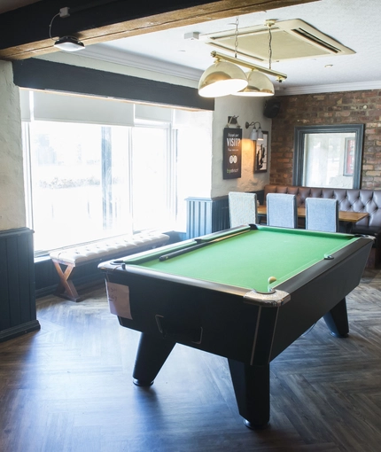 Interior dining area of a pub with a pool table.