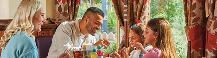 family sitting round a table in a restaurant eating cake and ice cream