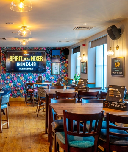 The interior restaurant seating area at the Counting House in Dumbarton, with brightly coloured wallpaper, and a TV on the wall.
