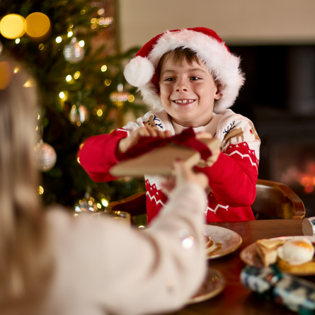 An image of an adult and child exchanging a gift while enjoying fruit juice and dishes from the Breakfast with Santa menu at Chef & Brewer venues.