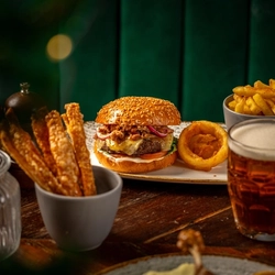 A plated burger and sides  on a festive decorated wooden table.
