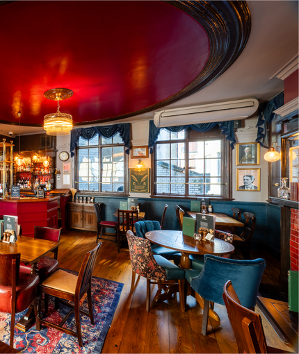 The interior restaurant seating area and small bar at the Two Chairmen in St James's, with upholstered seats, wooden flooring, and framed artwork on the walls.