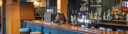 An image showing the interior bar area with bar stool seating and tiled flooring at The Sportsman.