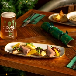 A wooden table, decorated with festive decoration is  holding a plated chicken liver pate.