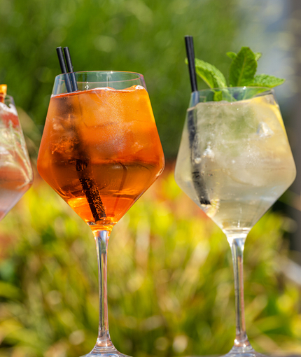 An advertising image of 3 cocktail style drink sat on a table within the exterior beer garden seating area at a Crafted venue.