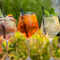 An advertising image of 3 cocktail style drink sat on a table within the exterior beer garden seating area at a Crafted venue.
