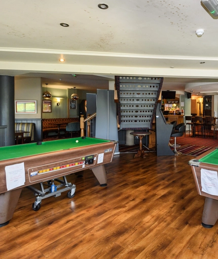 Interior dining area of a pub with two pool tables.