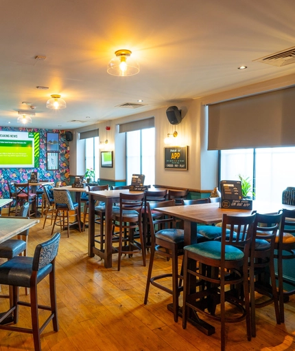 The interior restaurant seating area at the Counting House, with brightly coloured wallpaper, and a TV on the wall.
