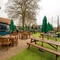 The exterior beer garden seating area of the Malvern Tavern, with wooden picnic tables, shade umbrellas, and string lights.