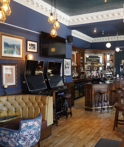 The interior bar and seating area with TV and pub games at Shakespeares in Edinburgh.