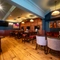 An interior restaurant seating area at the Phoenix; with TVs on the walls; and padded chairs, bar stools, benches, and booth seating.