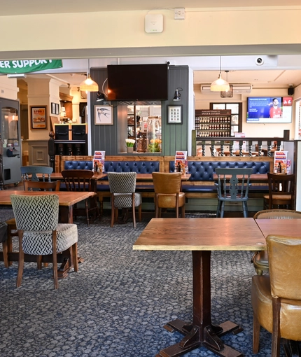 Interior dining area of a pub with a few TVs and a claw machine.