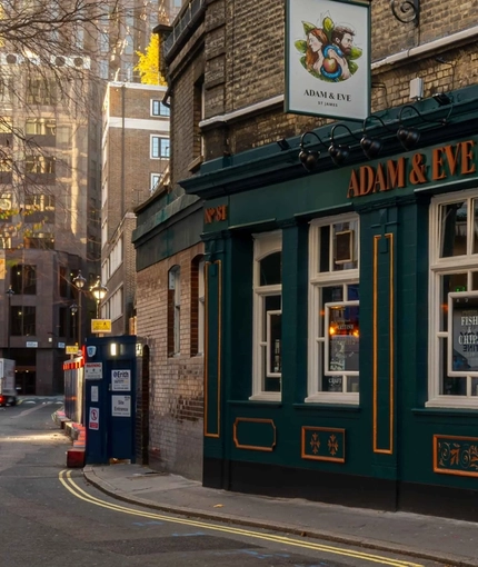 The exterior facade and signage of Adam & Eve in St James, with flower baskets hanging on each side of the door.