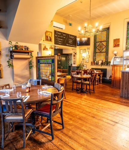 The interior restaurant seating area with tables laid out with cutlery, glasses and floral arrangements with the food cabinet counter in the background at The Morgan Arms.
