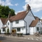 The exterior facade, signage, seating area, and car park of The Green Man in Great Offley, with accessible parking spaces near the entrance.