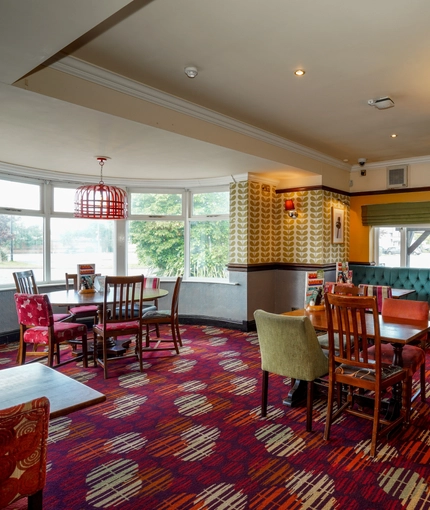 Interior dining area of a pub with a fireplace and a TV.