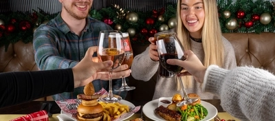 An interior shot of people celebrating Christmas and enjoying festive food in the restaurant/seating area at a Flaming Grill venue.