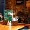 A close up view of salt, pepper, and a wooden box containing menus, cutlery, serviettes, and a bottle of tomato sauce, on a wooden restaurant table inside The Windmill Inn.