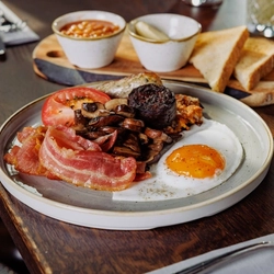 Full English plated with mushrooms, with a coffee.