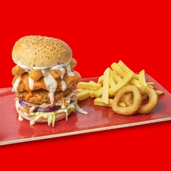 The Hungry Horse Signature Hot Buffalo Ranch Burger served on a red plate with fries and onion rings; on a bright red background.