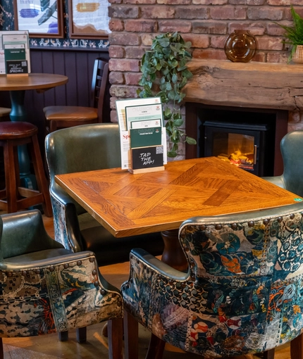 The interior restaurant seating area with tables, chairs and brick log burner fireplace at The Church View Inn.