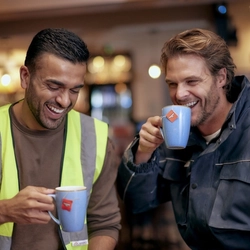 Two men holding and sipping mugs of tea.