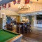 Interior dining area of a pub with a pool table, a bar and a TV.