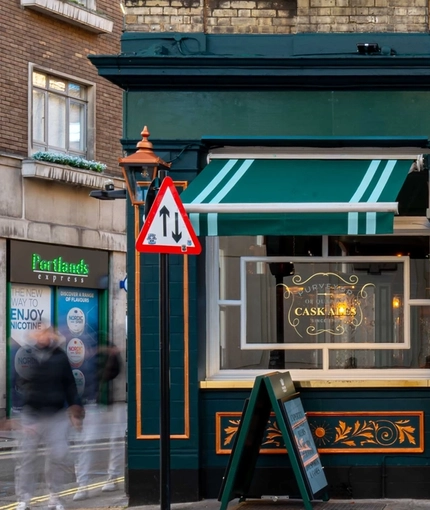 The exterior facade and signage of Adam & Eve in St James, with flower baskets hanging on each side of the door.